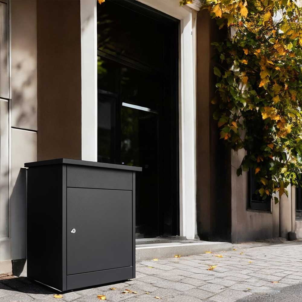Outdoor parcel box Puffin in anthracite grey, free-standing next to a front door