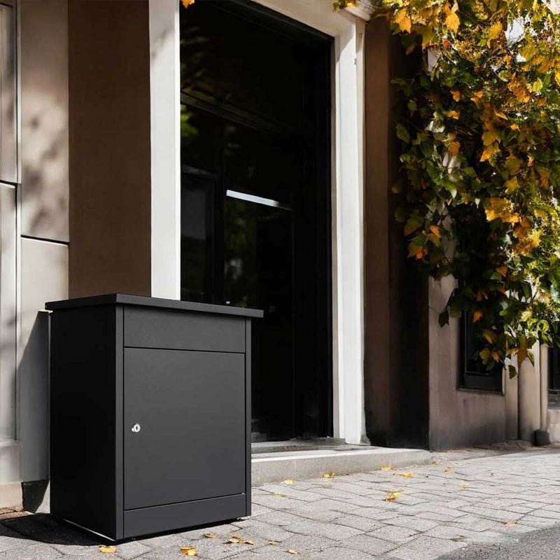 Outdoor parcel box Puffin in anthracite grey, free-standing next to a front door