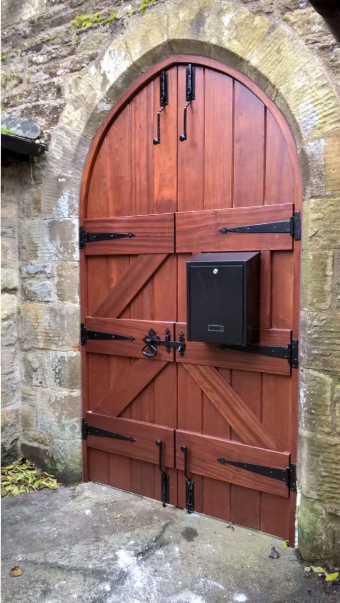 Wooden door with black hardware on a stone wall